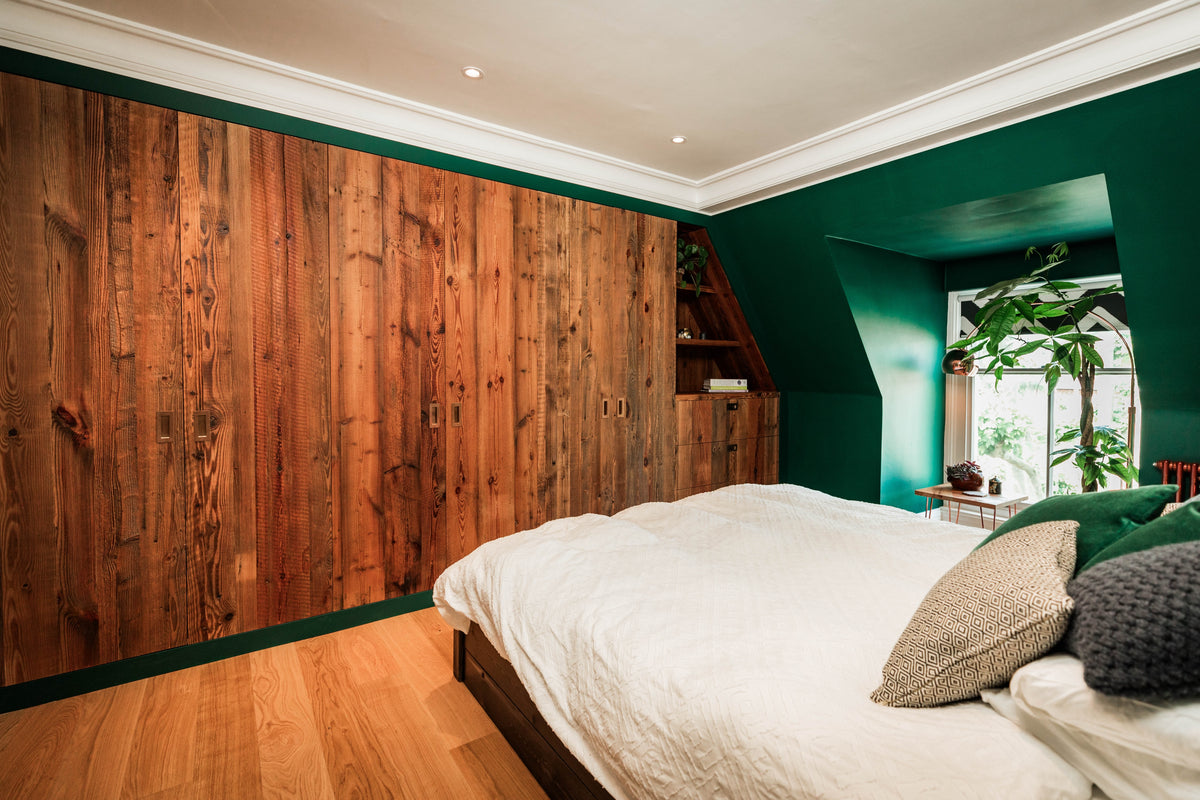 Reclaimed barn wood wardrobe doors in a green bedroom, with bespoke fitted cabinetry and matching built-in storage.