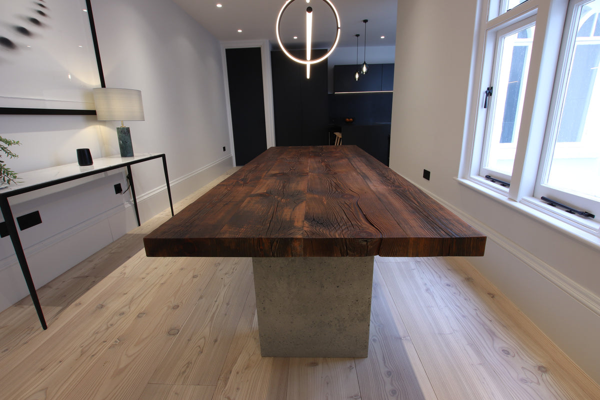 Characterful reclaimed wood dining table with thick solid wood top and concrete pedestal legs