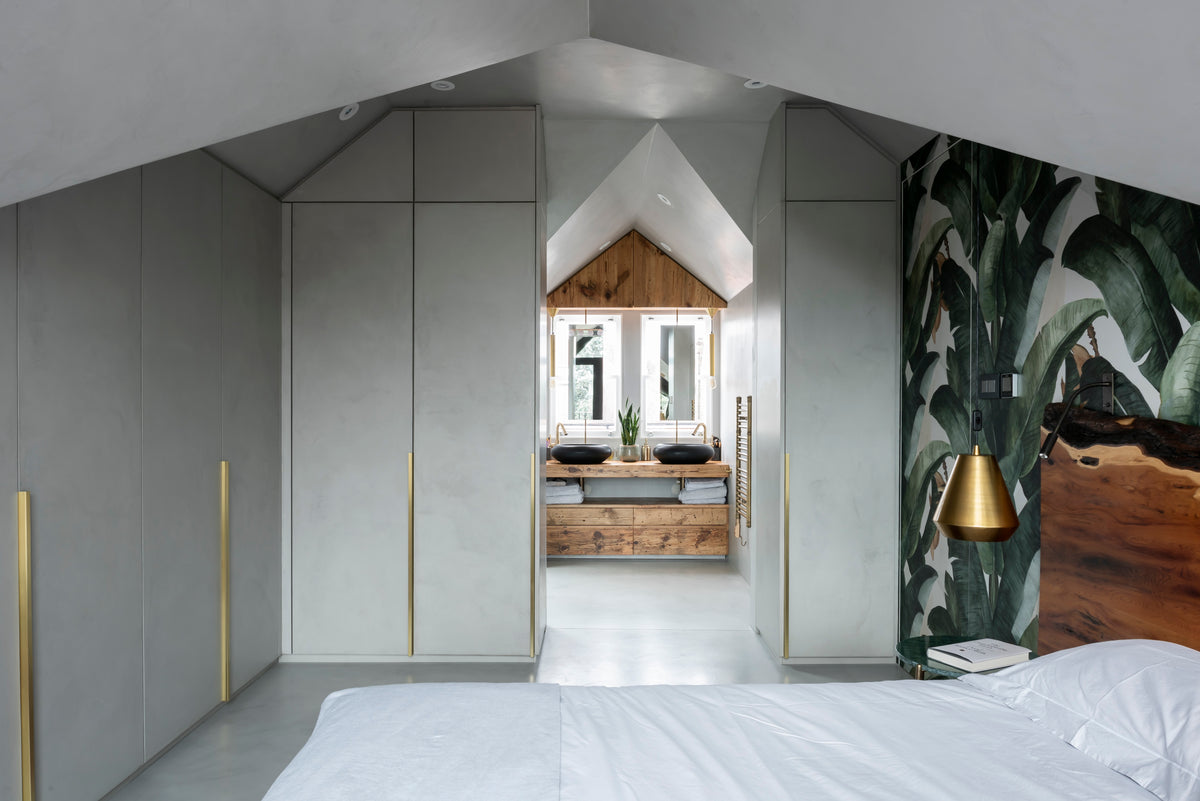 Concrete wardrobes with brass handles and a reclaimed barn wood bathroom vanity visible through the doorway plant wall paper slab wood headboard