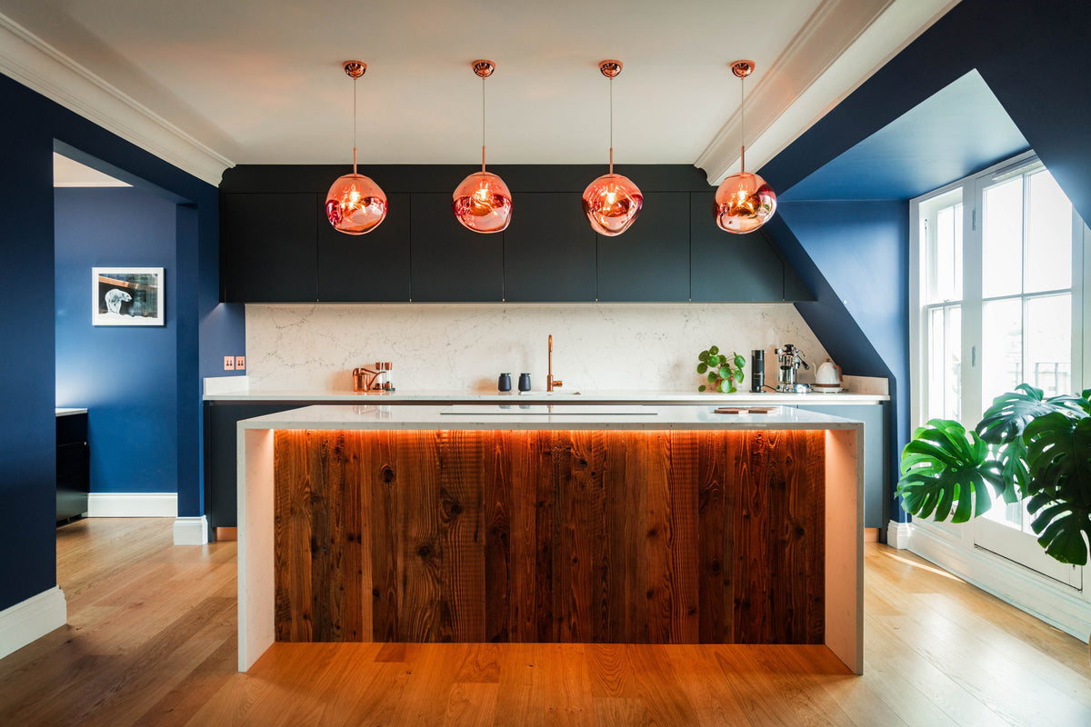 kitchen island with wooden cladding panel surrounded by fitted cabinetry the bespoke project with pendant lights