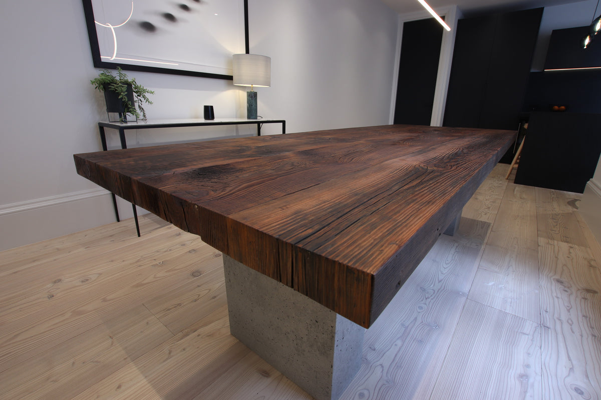 Solid wood dining table made from reclaimed barn wood with concrete base in a contemporary interior