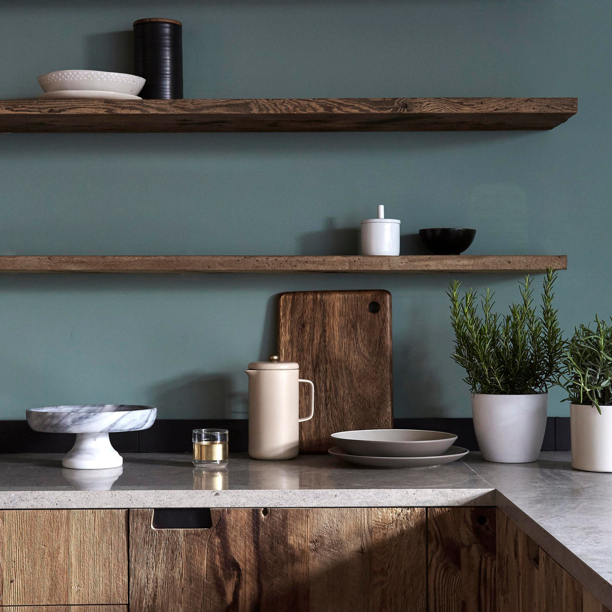 Reclaimed barn wood floating shelves and kitchen fronts with minimalist styling, including ceramics, plants and a marble worktop