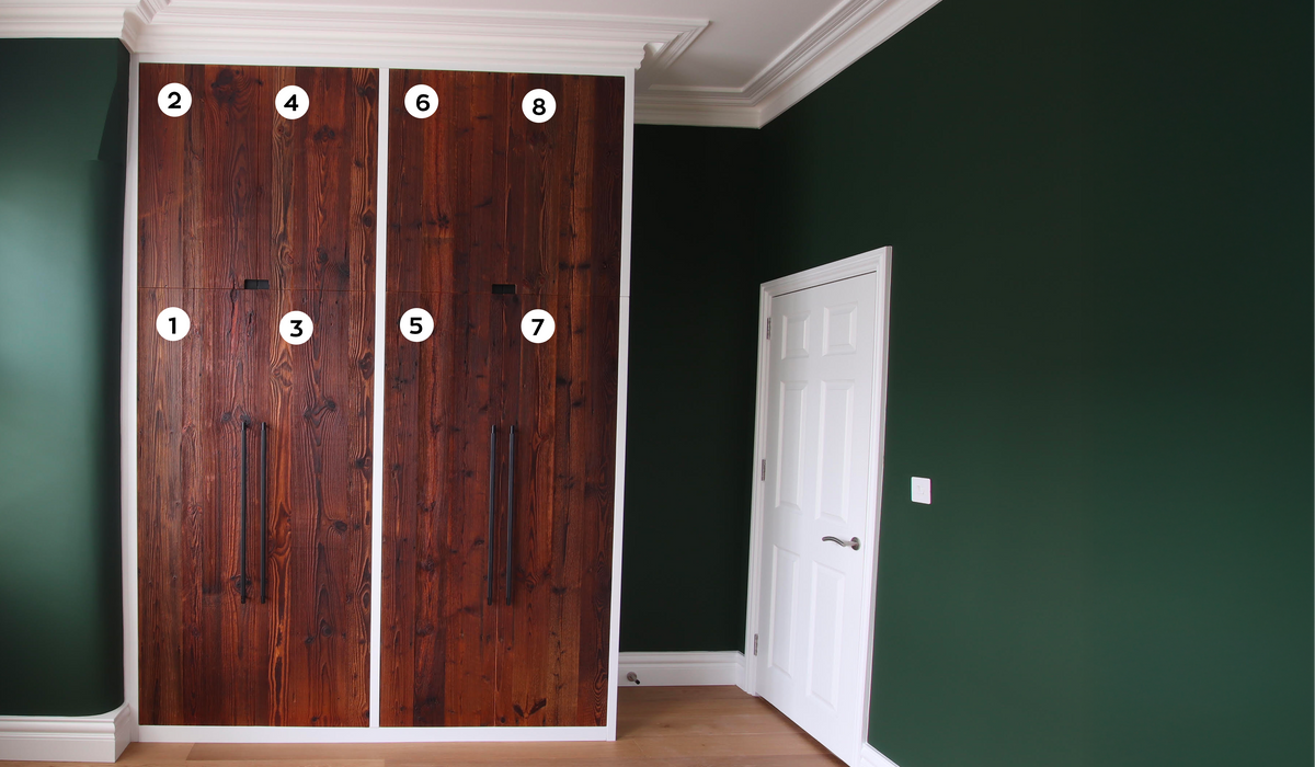 A set of eight dark brown wooden closet doors with white frames and black handles, shown installed in a room with dark green walls and light wood floors. White numbered circles (1-8) are overlaid on the doors.