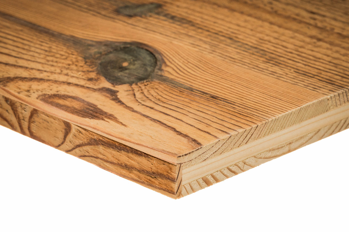 Close-up of a warm mid-tone brown reclaimed barn wood panel edge showing aged grain patterns and natural knots.